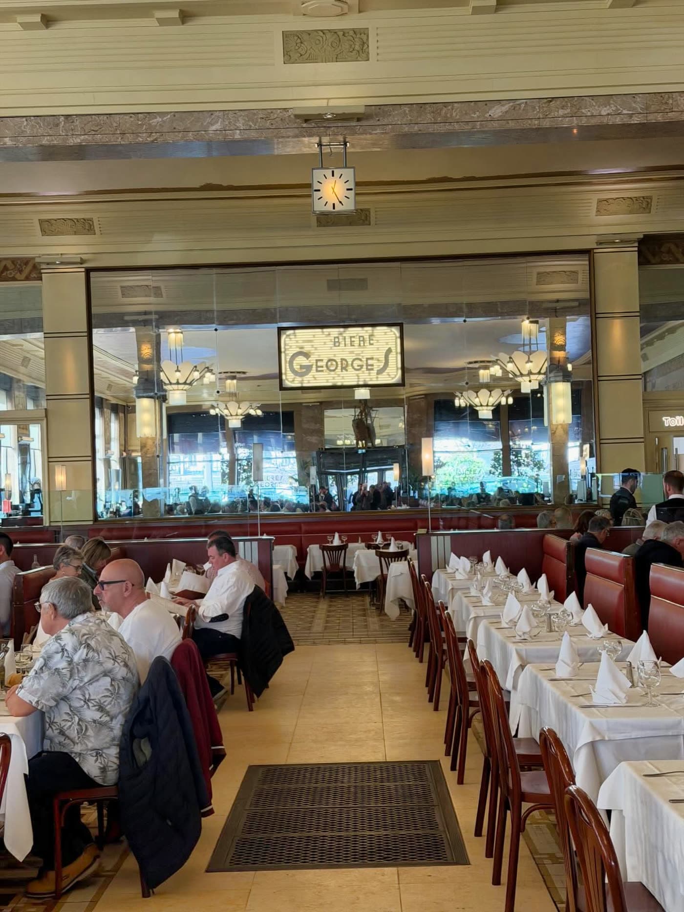 Vue de la grande salle Art déco avec colonnes, tables dressées et convives — Brasserie Georges