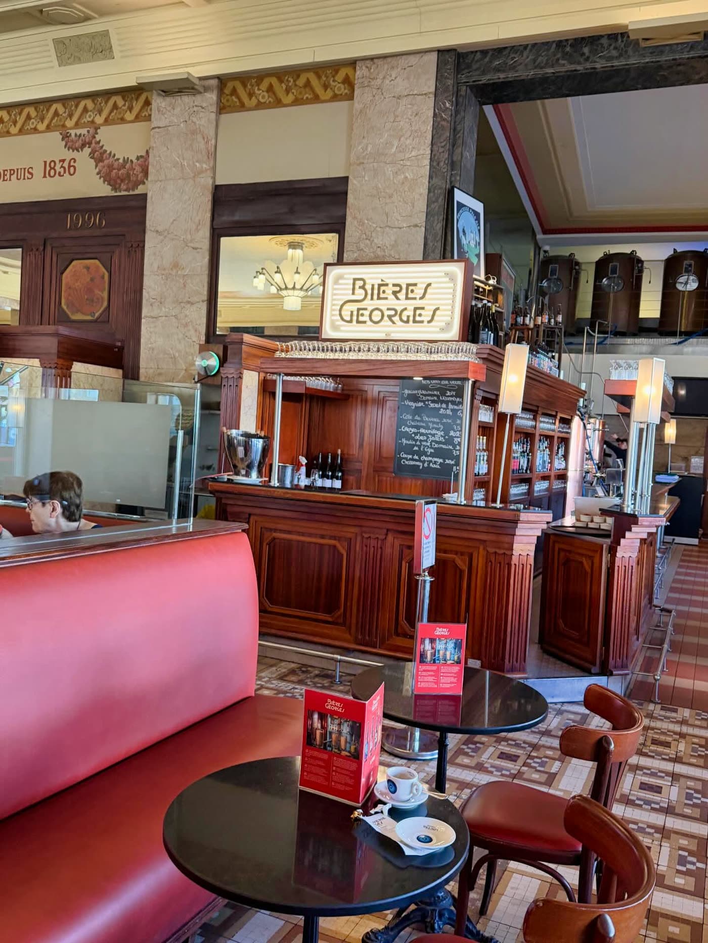 Comptoir bar en bois avec enseigne Bières Georges et banquette rouge — Brasserie Georges