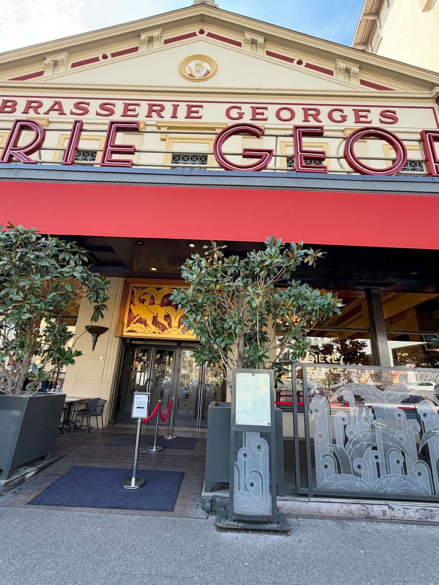 Façade et entrée de la Brasserie Georges de jour avec enseigne rouge et lettres dorées
