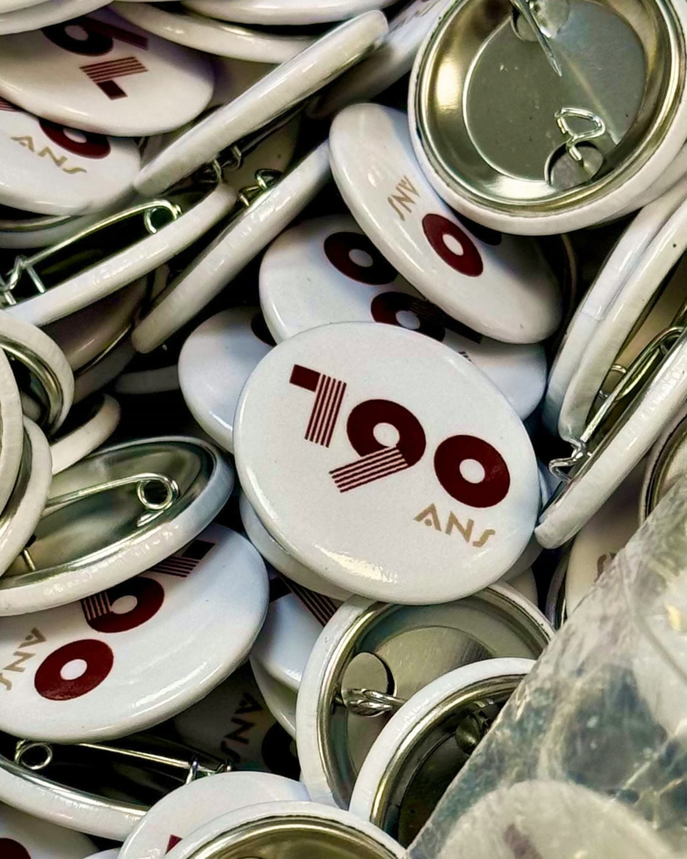 Gros plan d'un tas de badges promotionnels « 190 ANS » sur une table — Brasserie Georges