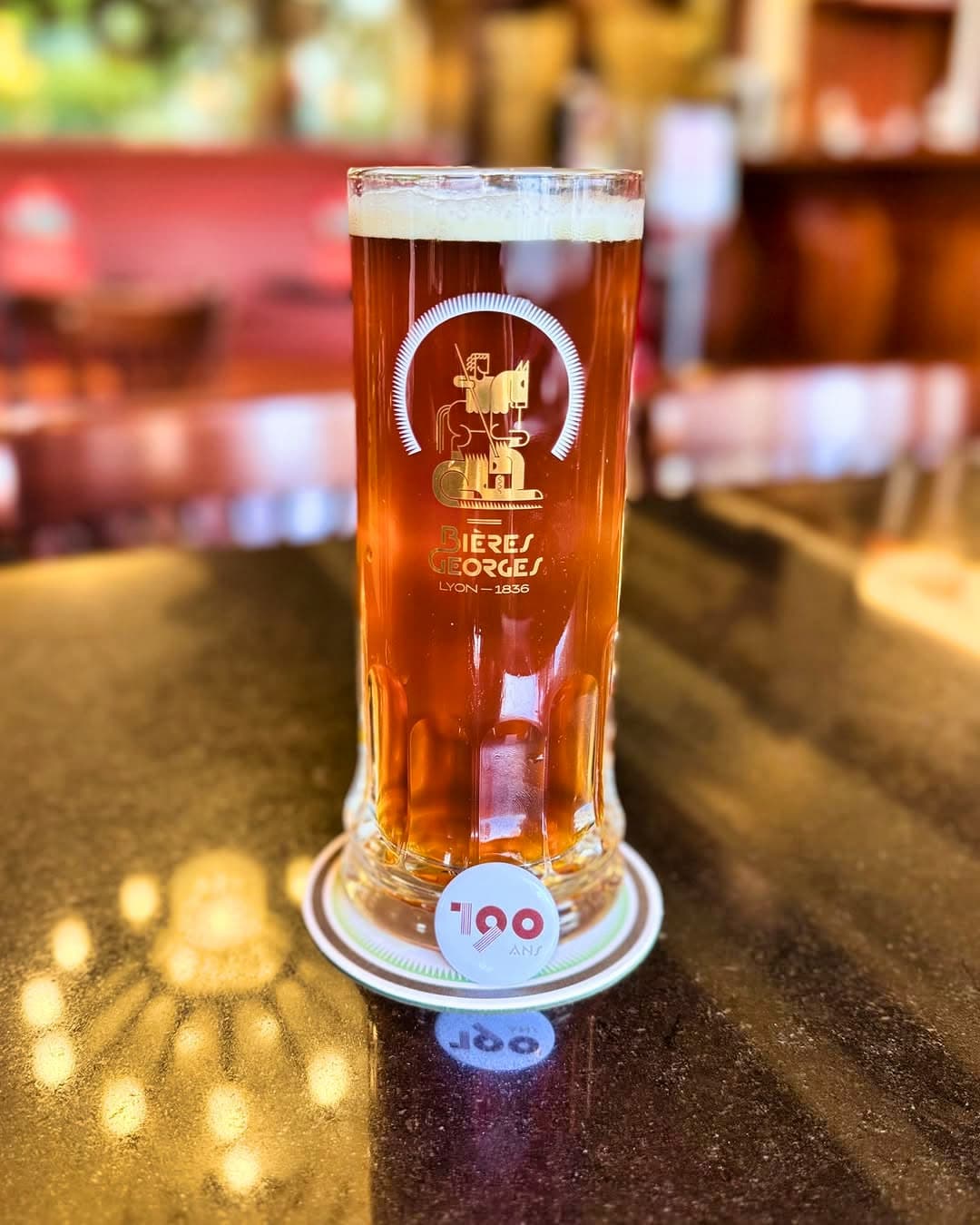 Chope de bière Bières Georges sur comptoir avec sous-bock « 190 ans », lumière chaude en bokeh — Brasserie Georges