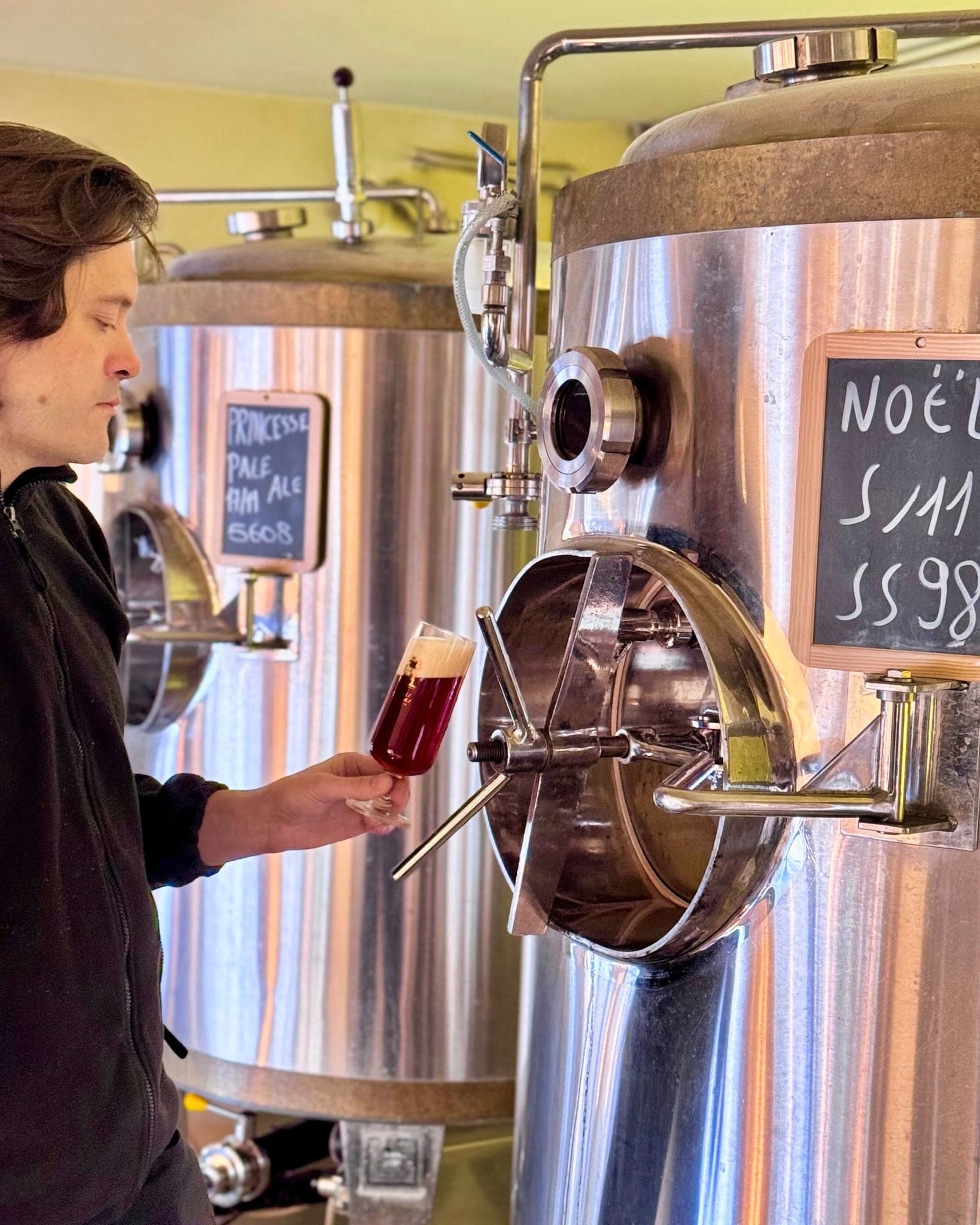 Le brasseur de la Brasserie Georges dégustant un échantillon devant les cuves de brassage en inox