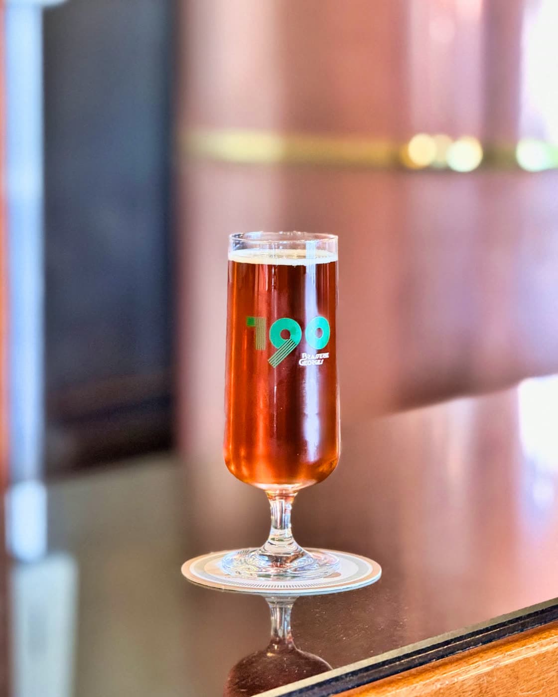 Un verre de bière ambrée logoté « 190 » posé sur le comptoir