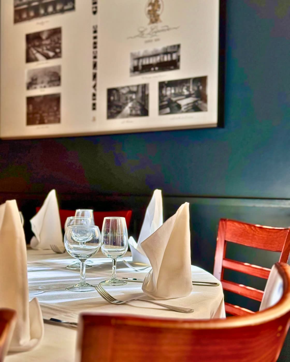 Une table dressée, verres et serviettes pliées, sous les photos d'archives