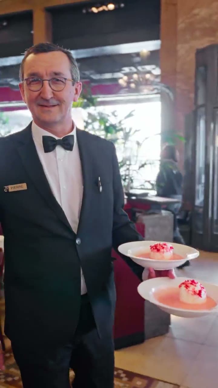 Un maître d'hôtel traverse la salle avec des assiettes de dessert aux pralines roses