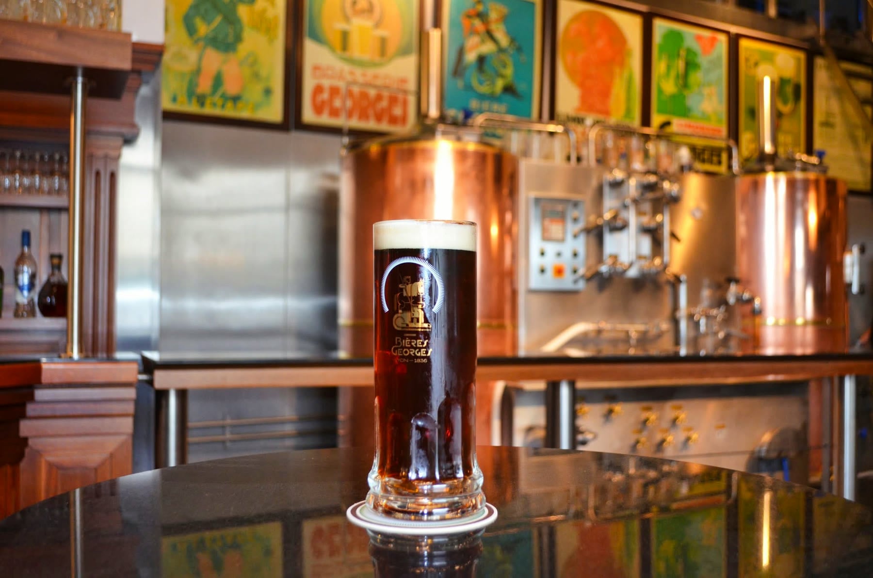 Une chope de bière Georges posée sur le bar, devant les cuves de brassage en cuivre