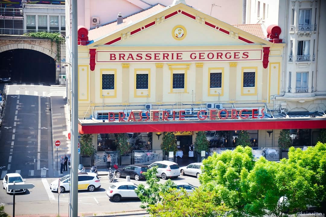 La façade de la Brasserie Georges vue d'en haut, son fronton jaune et son auvent rouge, sur le cours de Verdun animé