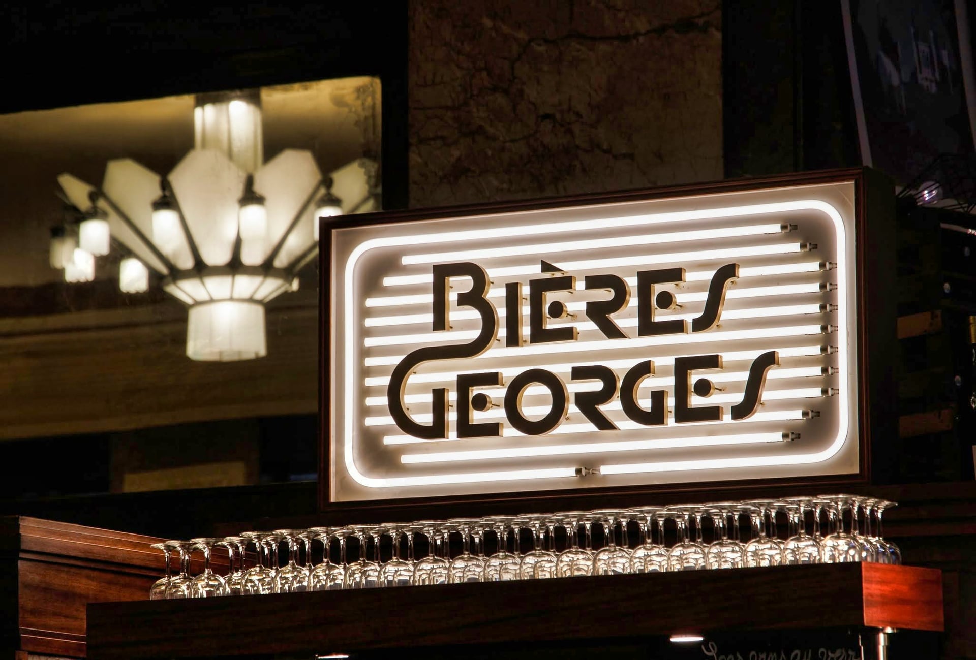 L'enseigne néon Art Déco « Bières Georges » au-dessus du bar de la Brasserie Georges, et sa rangée de verres